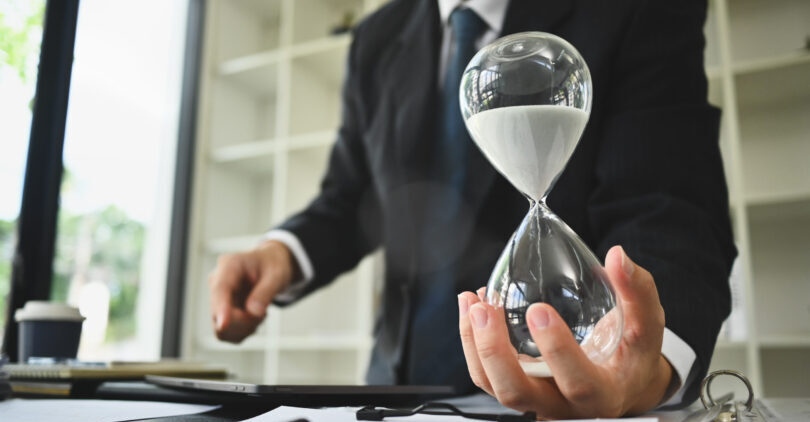 Hand of businessman holding hourglass. Business and time management concept.
